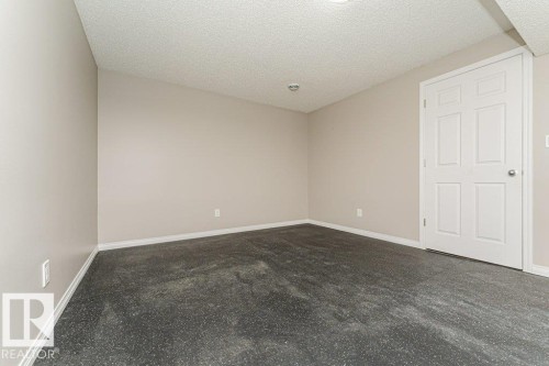 Neutral-toned walls, textured ceiling, six-panel interior door, and dark-toned flooring - 3203 Carpenter Landing Sw, Edmonton, AB 