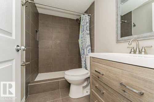 Vanity with wood-finish cabinetry, white countertop, and brushed nickel faucet - 3203 Carpenter Landing Sw, Edmonton, AB 
