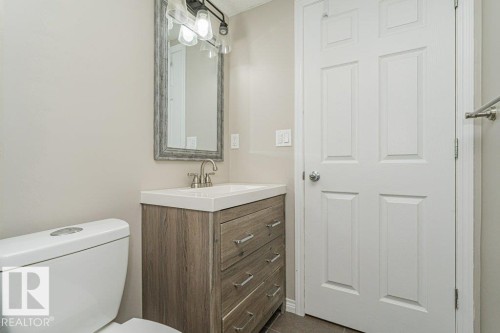 Vanity with wood-finish cabinetry, integrated sink, and brushed nickel faucet - 3203 Carpenter Landing Sw, Edmonton, AB 
