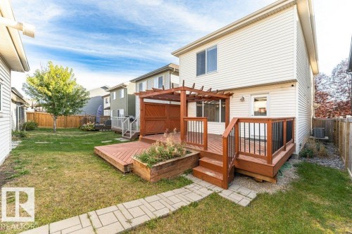 Multi-level wooden deck with pergola and built-in planter, stone paver pathway, and fenced backyard - 3203 Carpenter Landing Sw, Edmonton, AB 