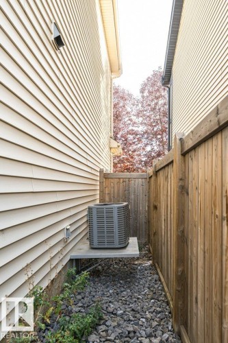 Air conditioning unit mounted on a raised platform, wood privacy fence, and gravel ground cover - 3203 Carpenter Landing Sw, Edmonton, AB 