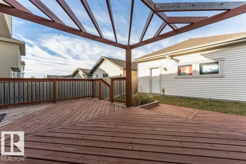 Expansive wood deck with a built-in pergola frame, geometric plank design, and wood railing - 3203 Carpenter Landing Sw, Edmonton, AB 