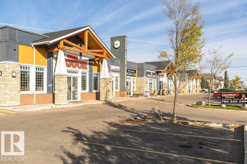 Strip mall featuring stone veneer accents, wood-beam entryways, and varied exterior siding - 3203 Carpenter Landing Sw, Edmonton, AB 