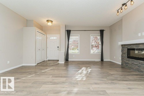 Wood-finish flooring throughout, stacked stone fireplace with mantle, track lighting, and a front entry with a built-in closet - 3203 Carpenter Landing Sw, Edmonton, AB 