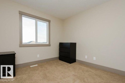 Wall-to-wall carpeting, neutral wall color, and a window with a mountain backdrop - 7233 Armour Crescent Sw, Edmonton, AB 
