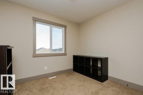 Carpeted interior with light-toned walls and a single window with a framed surround - 7233 Armour Crescent Sw, Edmonton, AB 