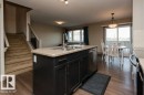 Kitchen island with dark cabinetry, stainless steel dishwasher, and a double-basin sink - 7233 Armour Crescent Sw, Edmonton, AB 