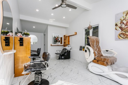 Vaulted ceiling with exposed beam, recessed lighting, ceiling fan, white tile flooring, and a large window - 7204 92B Avenue Nw, Edmonton, AB 