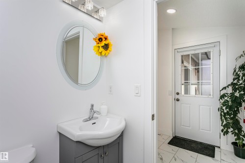 Pedestal sink with gray vanity, illuminated by a multi-bulb vanity light - 7204 92B Avenue Nw, Edmonton, AB 