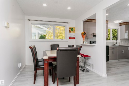 Light wood-finish flooring, recessed lighting, and a kitchen pass-through with breakfast bar - 7204 92B Avenue Nw, Edmonton, AB 