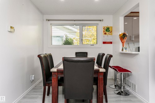 Dining area featuring light wood-finish flooring and a pass-through window - 7204 92B Avenue Nw, Edmonton, AB 