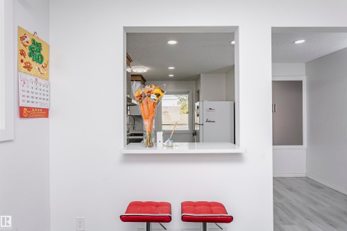 White painted walls, recessed lighting, wood-finish flooring, and a pass-through window with a white countertop - 7204 92B Avenue Nw, Edmonton, AB 