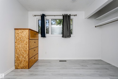 Light wood-finish flooring, white walls, and built-in shelving with a hanging rod - 7204 92B Avenue Nw, Edmonton, AB 