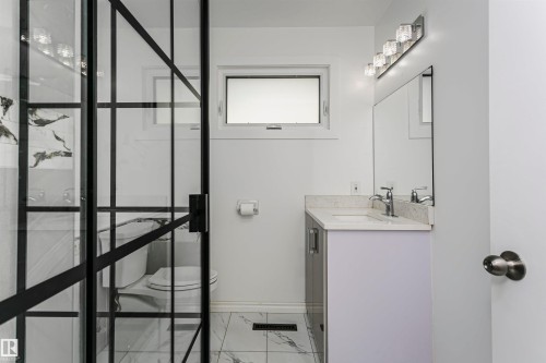 Modern black-framed glass shower enclosure with marbled tile surround - 7204 92B Avenue Nw, Edmonton, AB 