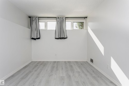 Light-toned wood-finish flooring, white walls, and white trim - 7204 92B Avenue Nw, Edmonton, AB 