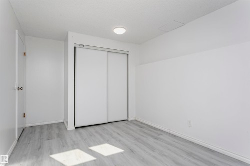 Light gray wood-finish flooring, white walls, and a ceiling-mounted light fixture - 7204 92B Avenue Nw, Edmonton, AB 