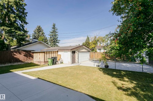 Detached garage with a roll-up door, concrete driveway, and chain-link fencing - 7204 92B Avenue Nw, Edmonton, AB 