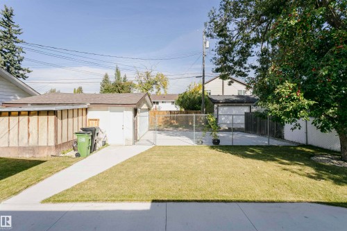 Expansive lawn area with a concrete pathway leading to a detached garage and paved parking - 7204 92B Avenue Nw, Edmonton, AB 