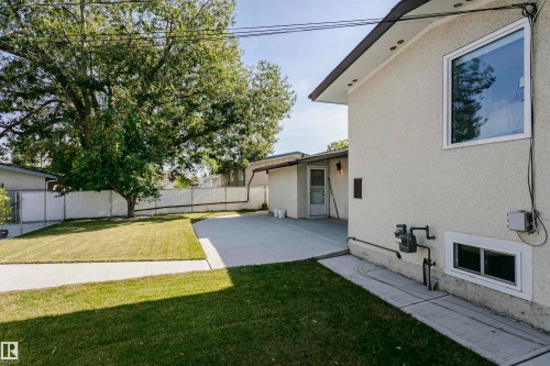 Exterior stucco finish, prominent window, concrete pathways, manicured lawn, and mature trees - 7204 92B Avenue Nw, Edmonton, AB 
