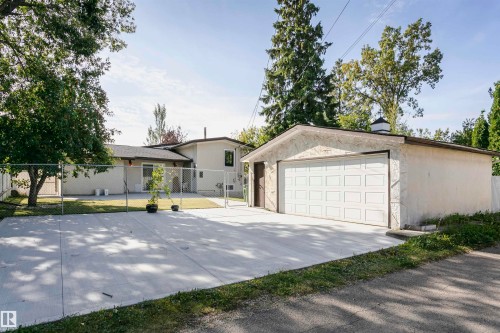 Detached garage with white panel door, concrete driveway, and chain-link fencing - 7204 92B Avenue Nw, Edmonton, AB 