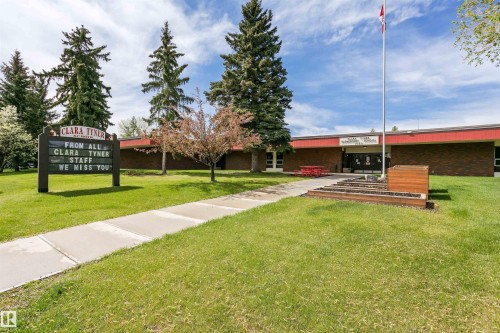 Manicured lawn with mature evergreen trees and a paved walkway leading to the building entrance - 7204 92B Avenue Nw, Edmonton, AB 