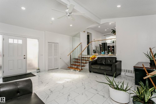 Recessed lighting and ceiling fan, white paneled entry door with transom windows, white bifold closet doors, staircase with wood treads and handrail, and white laminate flooring - 7204 92B Avenue Nw, Edmonton, AB 