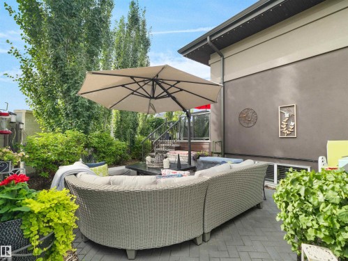 Private patio space featuring a paver stone surface, mature landscaping, and a metal railing staircase - 904 Wood Place Nw, Edmonton, AB 