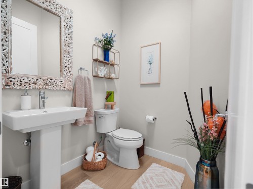 Pedestal sink with a polished chrome faucet, an ornate carved wood-frame mirror, and wood-finish flooring - 904 Wood Place Nw, Edmonton, AB 