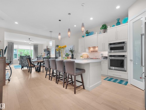 Kitchen featuring white cabinetry, stainless steel appliances, a center island with seating, and pendant lighting - 904 Wood Place Nw, Edmonton, AB 
