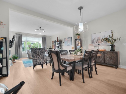 Light wood-finish flooring throughout, a geometric pendant light fixture, and a built-in sideboard with intricate detailing - 904 Wood Place Nw, Edmonton, AB 