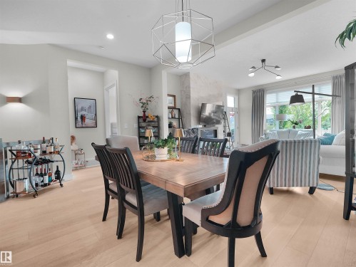 Open-concept living area featuring light wood-finish flooring, recessed lighting, and a modern geometric pendant light fixture - 904 Wood Place Nw, Edmonton, AB 