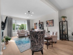 Bright living area featuring light wood-finish flooring, a large picture window, and a modern ceiling light fixture - 