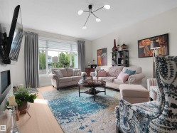 Recessed fireplace with a flat screen mount, light wood-finish flooring, large window with blinds and drapery, and a contemporary ceiling light fixture - 