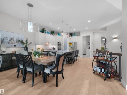 Open-concept living space featuring wood-finish flooring, recessed lighting, and a kitchen with an island, pendant lighting, and stainless steel appliances - 904 Wood Place Nw, Edmonton, AB 