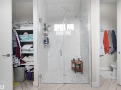 Glass-enclosed shower with large format tile walls and a mosaic tile floor - 