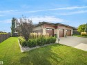 Contemporary exterior featuring stone accents, a multi-car garage with wood-finish doors, a concrete driveway, and landscaped garden beds - 904 Wood Place Nw, Edmonton, AB 