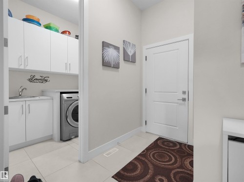 Laundry area featuring white cabinetry, a built-in sink, and light-toned tile flooring - 904 Wood Place Nw, Edmonton, AB 