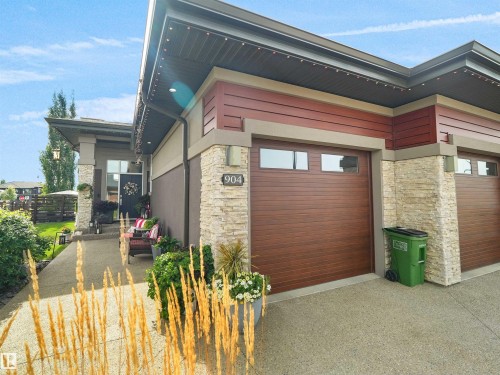 Exterior featuring stacked stone accents, horizontal siding, and a wood-finish garage door with windows - 904 Wood Place Nw, Edmonton, AB 