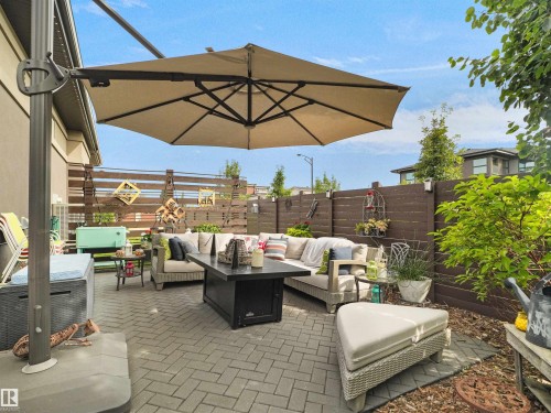 Paved patio area featuring a built-in fire pit, privacy fence, and mature landscaping - 904 Wood Place Nw, Edmonton, AB 