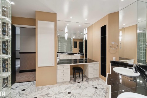 Dual vanity sinks, built-in makeup vanity, full-height mirrors, recessed lighting, and glass block wall - #12A 10050 118 St Nw, Edmonton, AB 