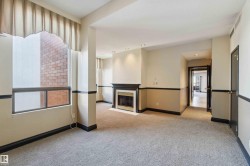 Recessed lighting, a fireplace with a black mantel and white surround, and light-toned carpet flooring - 