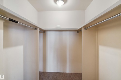 Custom closet system featuring multiple hanging rods, built-in shelving, and recessed ceiling light - #12A 10050 118 St Nw, Edmonton, AB 