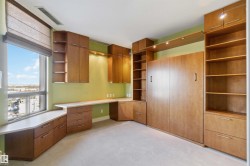 Built-in desk and storage cabinetry, integrated wall bed, wall-mounted shelving, and carpet flooring - 