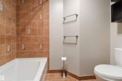 White bathtub with bronze-toned tile surround featuring decorative accents - 