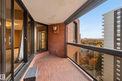 Balcony with brick-patterned flooring, glass railing, and a wall-mounted sconce - #12A 10050 118 St Nw, Edmonton, AB 