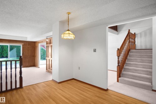 Hardwood flooring, carpeted staircase with wood banister, wall paneling, and sliding glass doors - 12311 25 Avenue Nw, Edmonton, AB 
