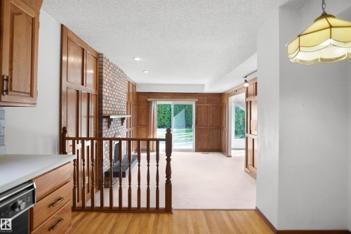 Wood-finish flooring leading to a carpeted living area with wood paneling - 12311 25 Avenue Nw, Edmonton, AB 