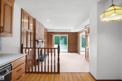 Wood-finish flooring leading to a carpeted living area with wood paneling - 