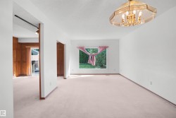 Open-concept living space with light-colored carpeting, white walls, and a large picture window - 