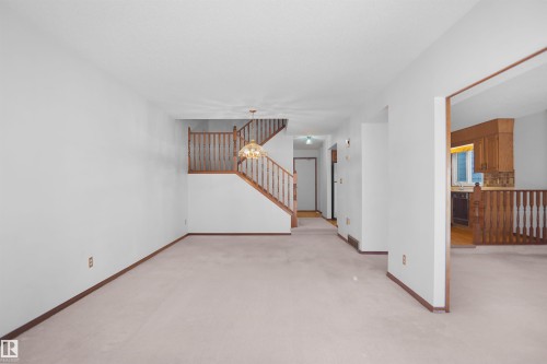 Open-concept living space with light-toned carpeting and white walls - 12311 25 Avenue Nw, Edmonton, AB 